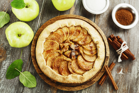 Baked galette or open pie with apples and cinnamon on the tableの写真素材