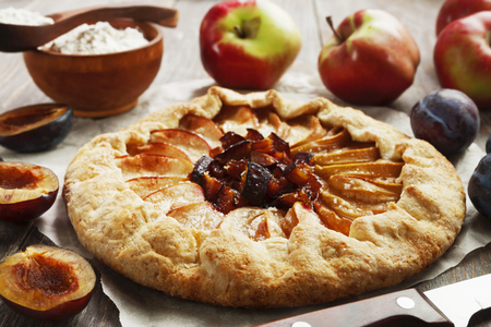 Galette or open pie with apples and plums on the tableの写真素材