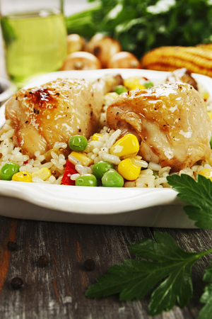 Chicken legs baked with rice and vegetables on the tableの写真素材