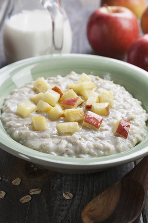 Oatmeal with caramelized apples in a ceramic plate on a wooden tableの写真素材