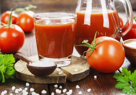 Tomato juice in a glass jug on a wooden tableの写真素材