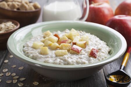 Oatmeal with caramelized apples in a ceramic plate on a wooden table