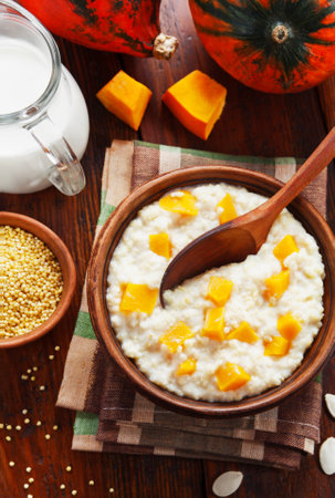 Millet porridge with pumpkin and milk in a pot on the tableの写真素材