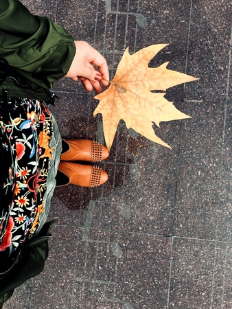 Young girl, city, autumn and maple leaf. Musical notes on the street tiles.の写真素材