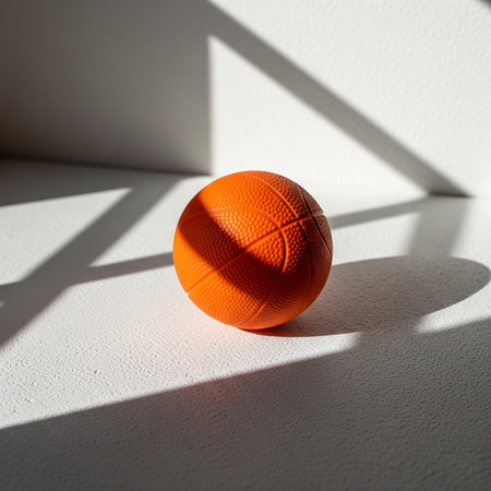 Orange basketball ball on a white wall with shadow. Sport concept.の素材