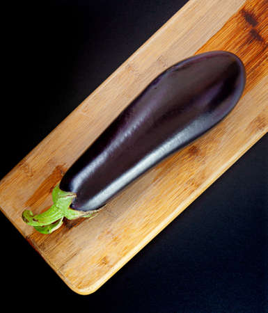 An eggplant on a wooden cutting boardの写真素材