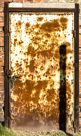 Texture of old cracked paint metal door in brick wallの写真素材