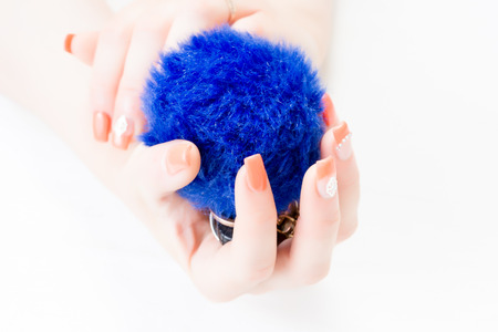 A woman's hand holds car keys and electronic door unlock with a blue fluffy ball keychain isolated on white background. Nail with artの写真素材