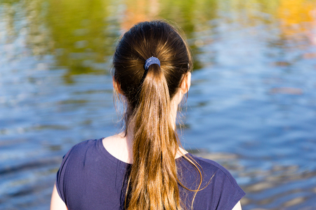 young woman looking at the water. showing backの写真素材