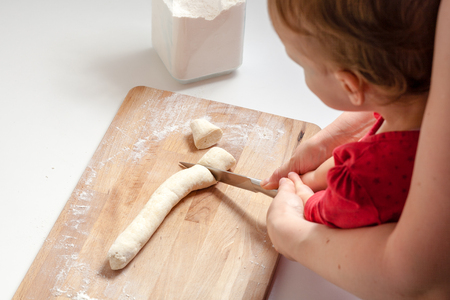 Mother and child daughter girl are cooking in the kitchen. Homemade food and little helper.の写真素材