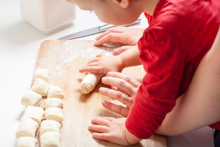 Mother and child daughter girl are cooking in the kitchen. Homemade food and little helper.の写真素材
