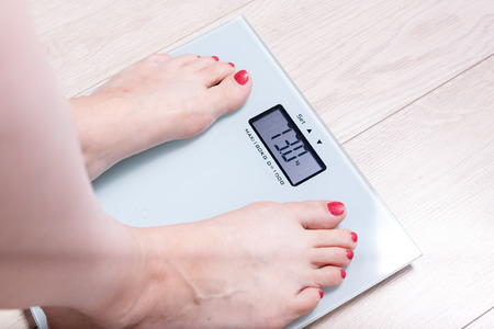 Female bare feet standing on a digital scales. Weight lossの写真素材