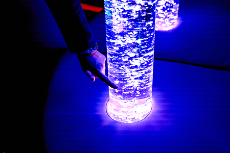 therapy sensory stimulating multi sensory room, woman interacting with colored lights bubble tube lamp during therapy healthcare retirement home sessionの写真素材
