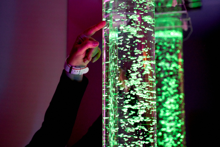 therapy sensory stimulating multi sensory room, woman interacting with colored lights bubble tube...