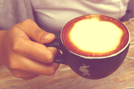 Hand holding a cup of coffee with close up shot in vintage toneの写真素材