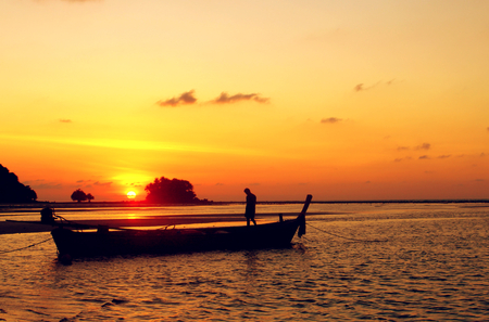 The silhouette of fishing boat on the sea with sunset background, orange sunlightの写真素材