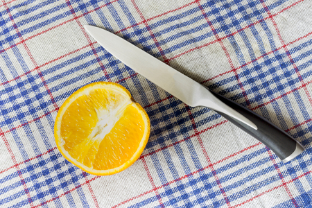 The orange slice and the knife on the tableclothの写真素材