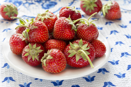 Juicy ripe strawberry on a white plate that stands on a table with a tableclothの写真素材