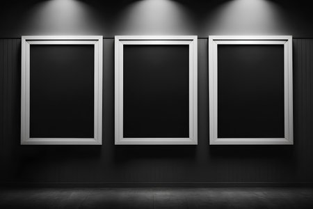Three empty frames on a black wall in a room with a wooden floorの素材