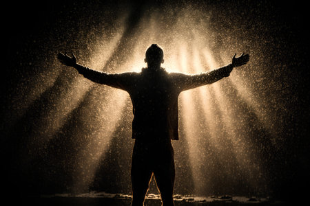 Silhouette of a man in the rain with hands raised upの素材