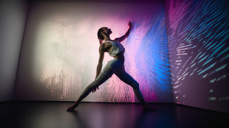 Silhouette of a young woman doing yoga in a room with colored lightsの素材