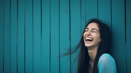 Portrait of a laughing young woman on a blue wooden wall backgroundの素材