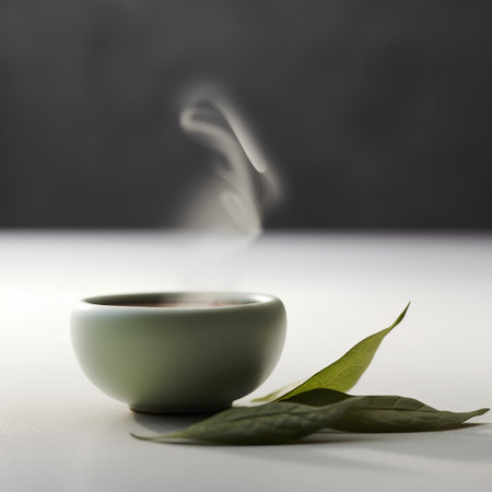 Green tea cup with steam and green leaves on the white table.の素材