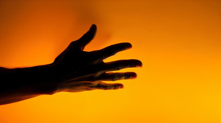 Silhouette of a man's hand on an orange background.の素材