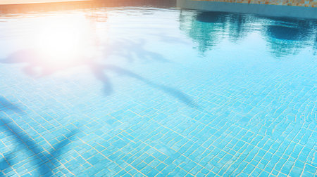 silhouette of a man jumping into a swimming pool on a sunny dayの素材