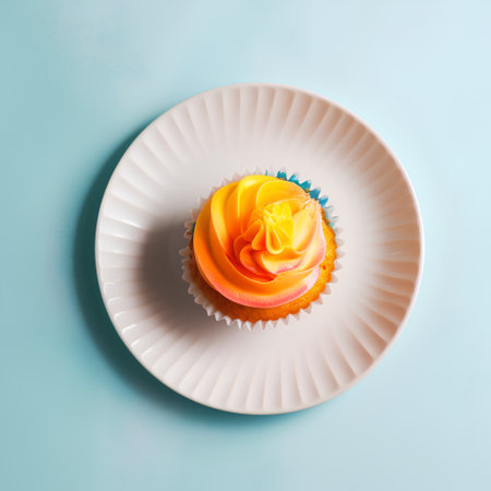 Cupcake with a yellow rose on a white plate on a blue backgroundの素材