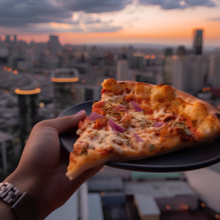 pizza in hand on the background of the city and the sunsetの素材