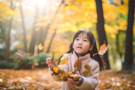 Portrait of a cute little girl playing with autumn leaves in the parkの素材