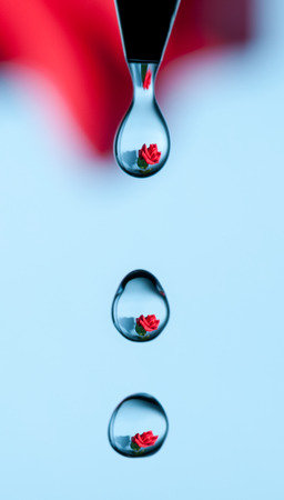 A rose caught reflected in a series of drips of water from a faucetの写真素材
