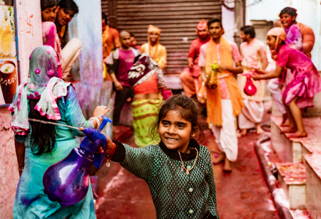Nandgeon, India, Holi Festival, Feb 25, 2018 - Girl sprays people with paint filled water while smiling, along with others in backgroundのeditorial素材