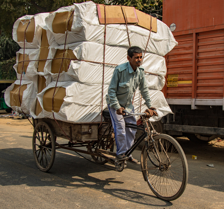New Dehli, India, Feb 19, 2018: Man carrying massive load on bicycle in Indiaのeditorial素材