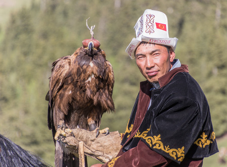 Issyk Kul, Kyrgyzstan - May 29, 2017: Eagle Hunter holds his eagles on horseback