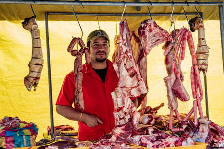 Cuenca, Ecuador, Jan 28, 2018: Man stands behind hanging meat in his market stall in Ecuadorのeditorial素材