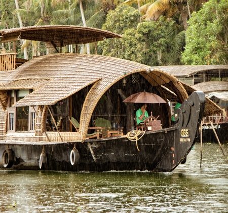 ALLEPPEY, INDIA, MAR 13, 2018: Bamboo thatched houseboat floats down the backwaters of Kerala in the rainのeditorial素材
