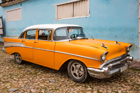 Trinidad, Cuba, Nov 28, 2017 - Orange Classic 1950's Chevrolet is parked in front of a homeのeditorial素材
