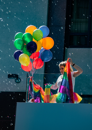 SAN FRANCISCO, CALIFORNIA, JUNE 24, 2018:  GAY PRIDE PARADE - Woman prepares balloons amid bubbles for a party overlooking paradeのeditorial素材