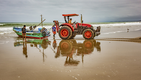 San Pedro, Ecuador - September 14, 2018 - fishing boats being pulled onto beach with tractorのeditorial素材