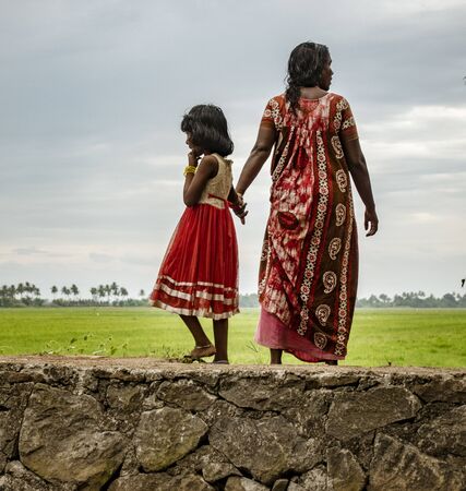 ALLEPPEY, INDIA, MAR 13, 2018: Mother and daughter stand on bank of canal holding handsのeditorial素材