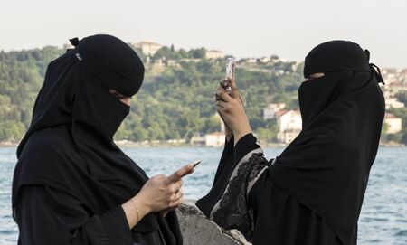 Ortakoy, Turkey - May 30, 2016 - Woman in hijab reads a message on her phoneのeditorial素材