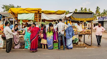 BADAMI, INDIA, MAR 18, 2018: People crowd around food stalls in small roadside market before going homeのeditorial素材