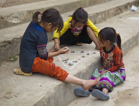 Sapa, Vietnam - Oct 22, 2011: Three girls play a game on school stepsのeditorial素材