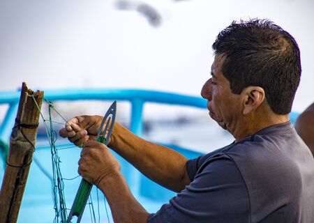 Puerto Lopez, Ecuador - Aug 19, 2016: Fisherman repairs his fishing nets in Puerto Lopez, Ecuadorのeditorial素材