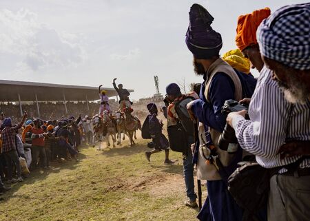 PUNJAB, INDIA, MARCH 2, 2018: Hola Mohalla Festival - Two men ride four horses, standing on their backs, as they race within inches of the audienceのeditorial素材