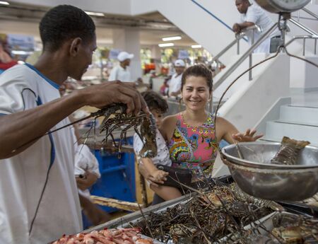 Panama City, Panama, Dec 5, 2017 - Woman holds child while smiling at lobster she is about to buyのeditorial素材