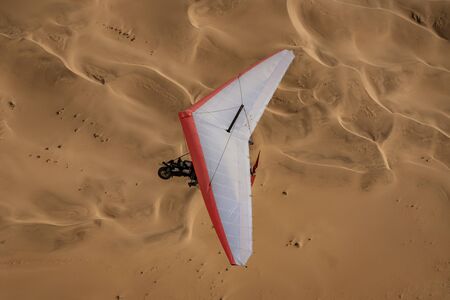 Walvis Bay, Namibia - July 16, 2018: An ultralight aircraft is seen flying with sand dunes as a backdrop in Namibiaのeditorial素材