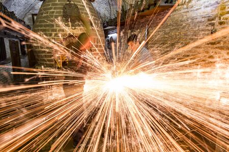 Bukhara, Uzbekistan - May 22, 2017 - Two blacksmiths use hammers to beat hot metal as sparks flyのeditorial素材